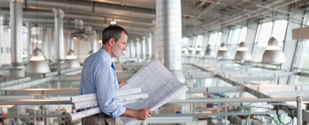 Man looking at blueprints in a new industrial construction